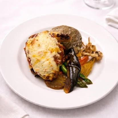 Grilled seafood with melted cheese and vegetables on a white plate