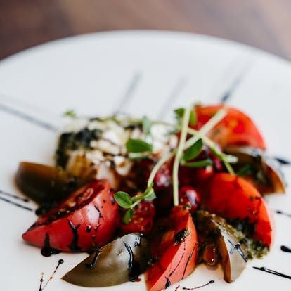 Plated strawberry dessert with chocolate drizzle and mint garnish on a white dish
