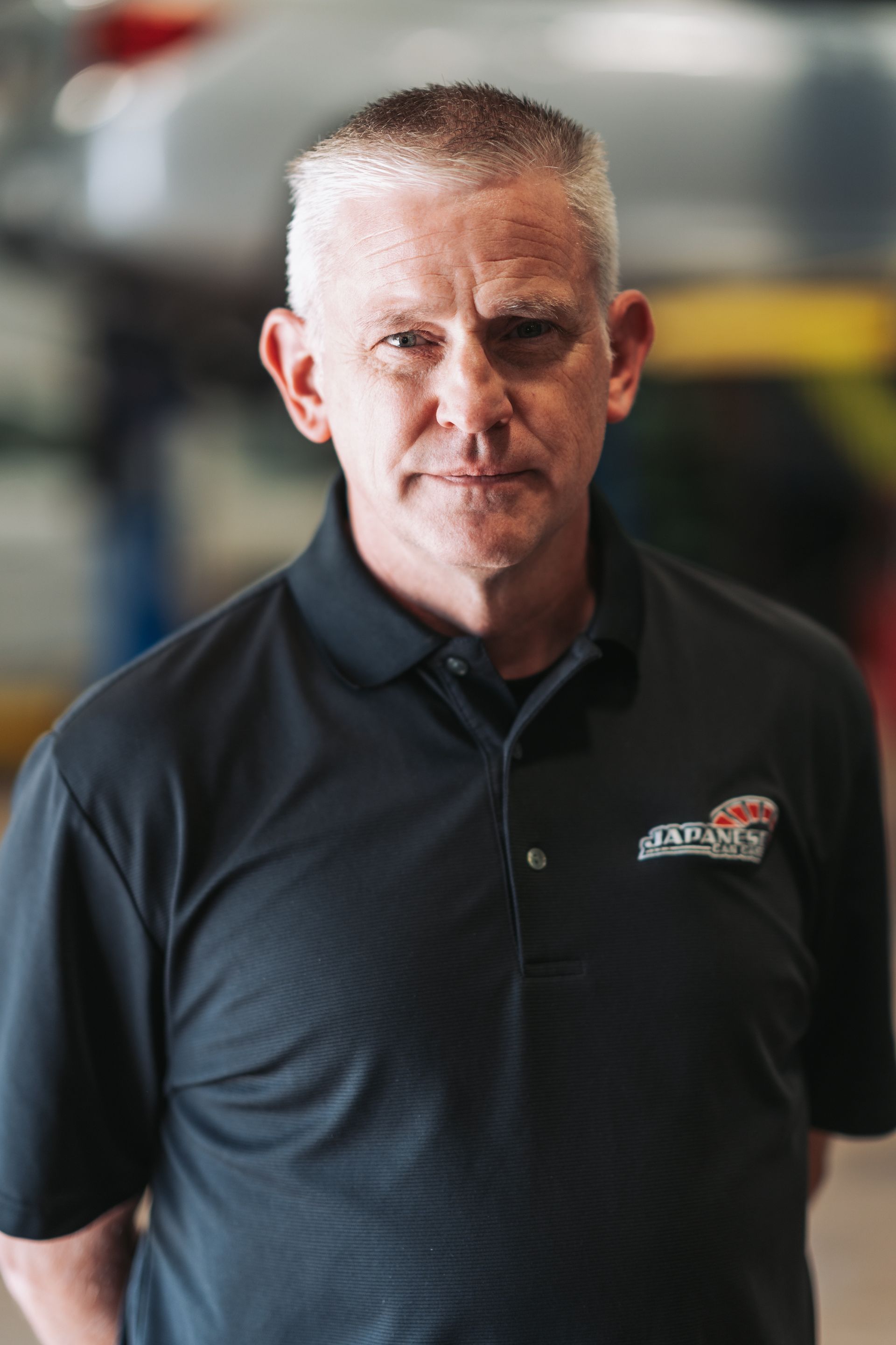A man in a black shirt is standing in front of a car. | Japanese Car Care