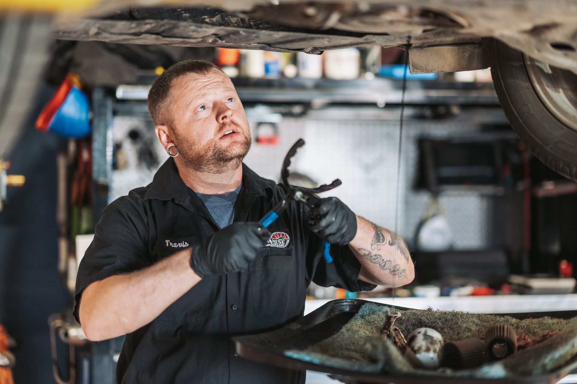 A man is working under a car in a garage. | Japanese Car Care