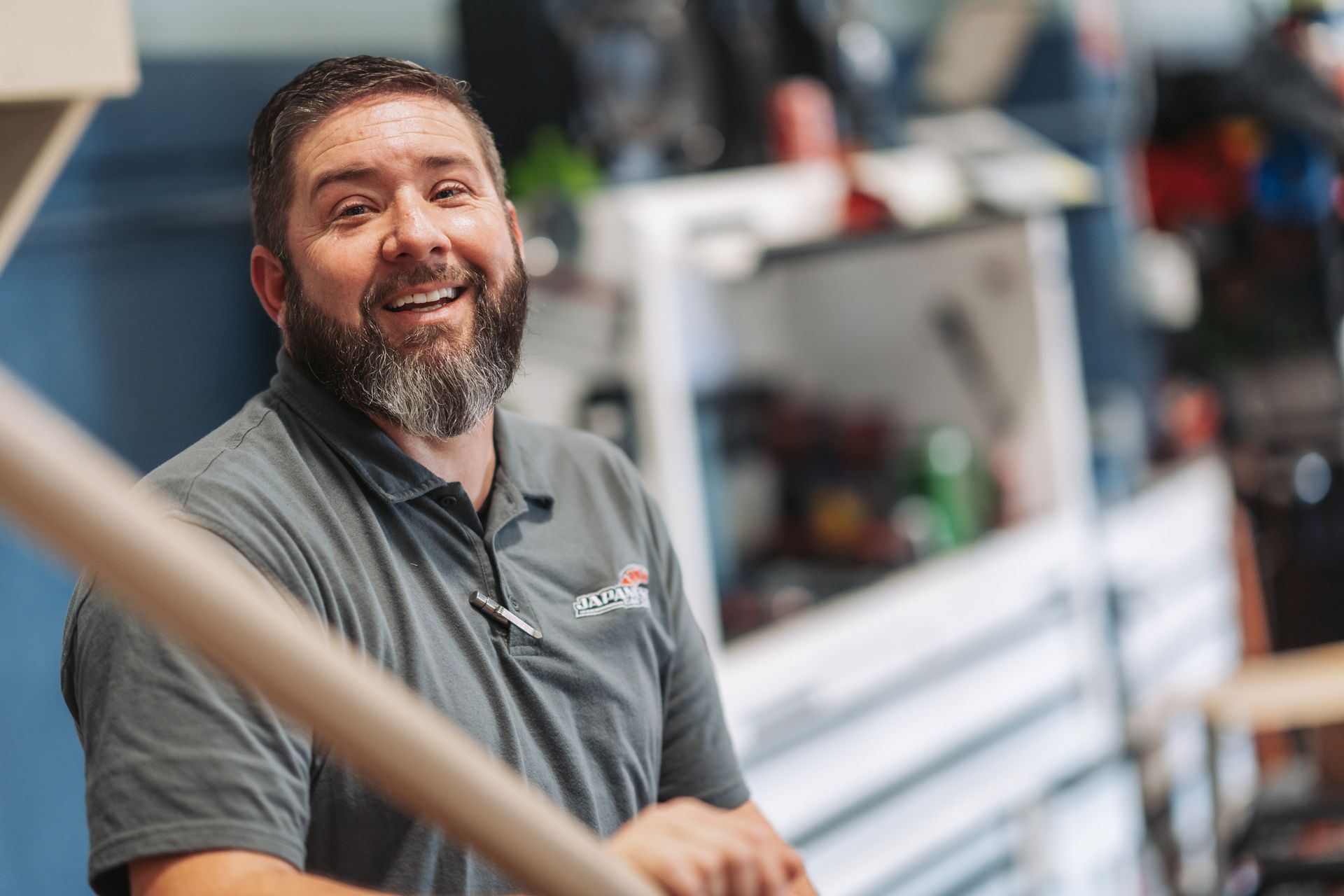 A man with a beard is smiling while standing on a set of stairs. | Japanese Car Care
