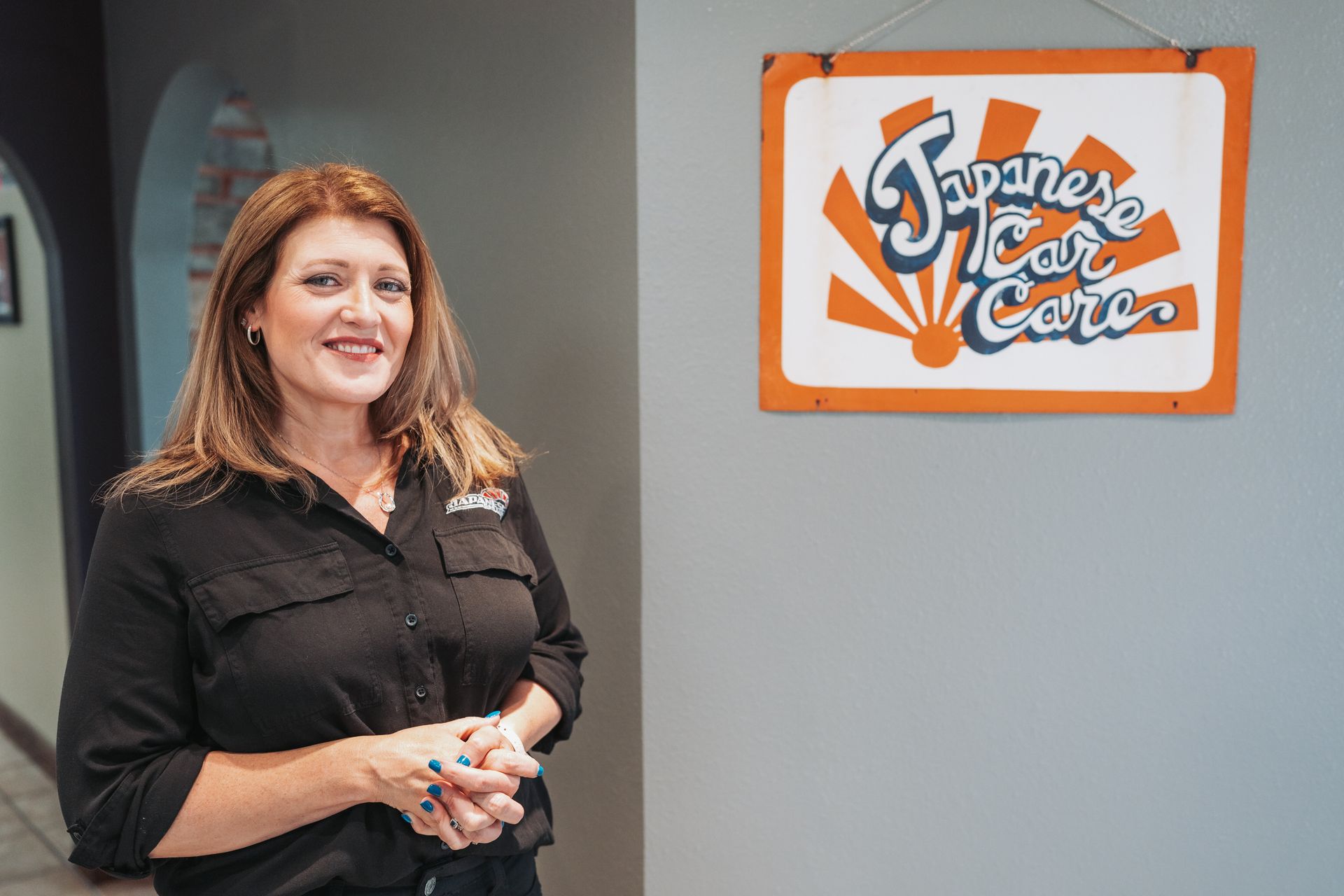 A woman is standing in front of a sign that says japanese car care. | Japanese Car Care