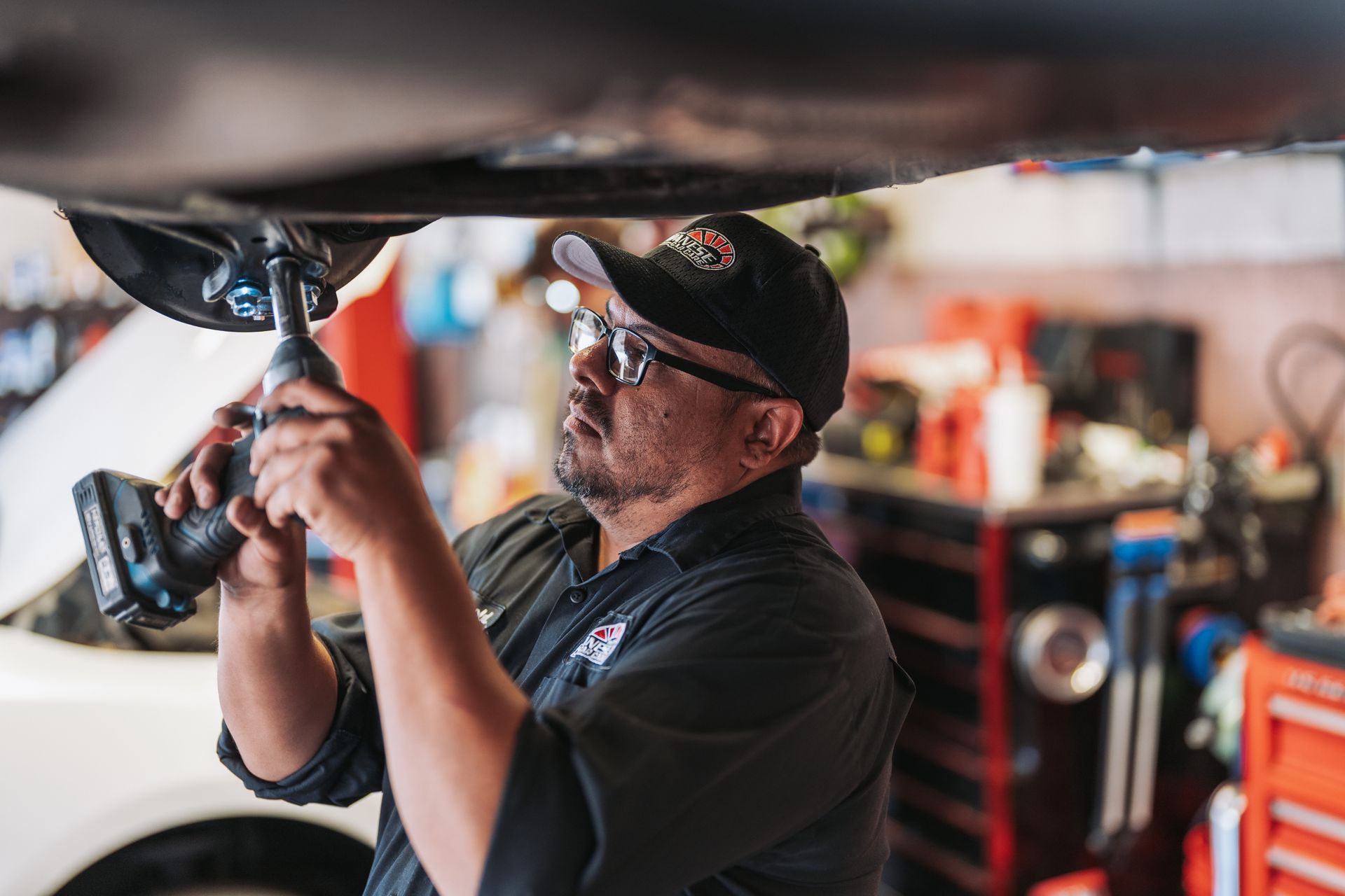 A man is working under a car with a drill. | Japanese Car Care