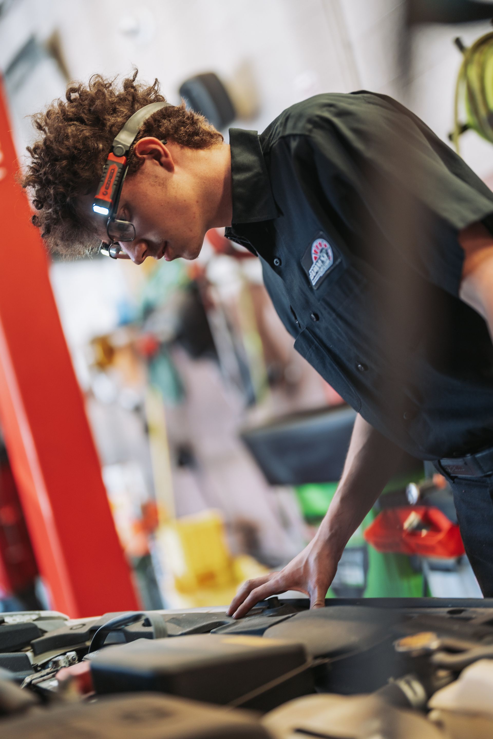A young man is working on a car in a garage. | Japanese Car Care