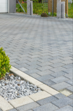 Gray paved driveway with a white curb and gravel border near a modern house entrance