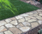 Stone garden path beside green grass and mulch