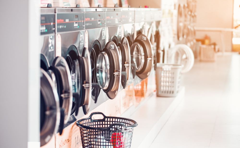 A Row of Washing Machines and Laundry Baskets in a Laundromat — Super Suds Commercial Laundry in Avoca, QLD