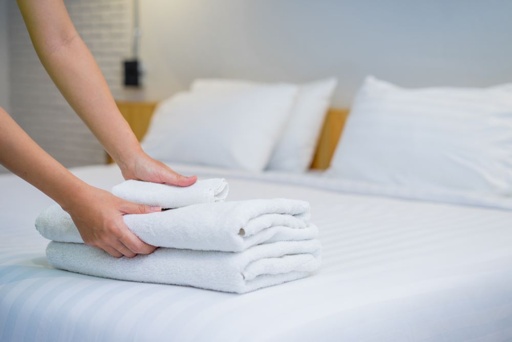 A Person is Stacking Towels on Top of Each Other — Super Suds Laundry in Avoca, QLD