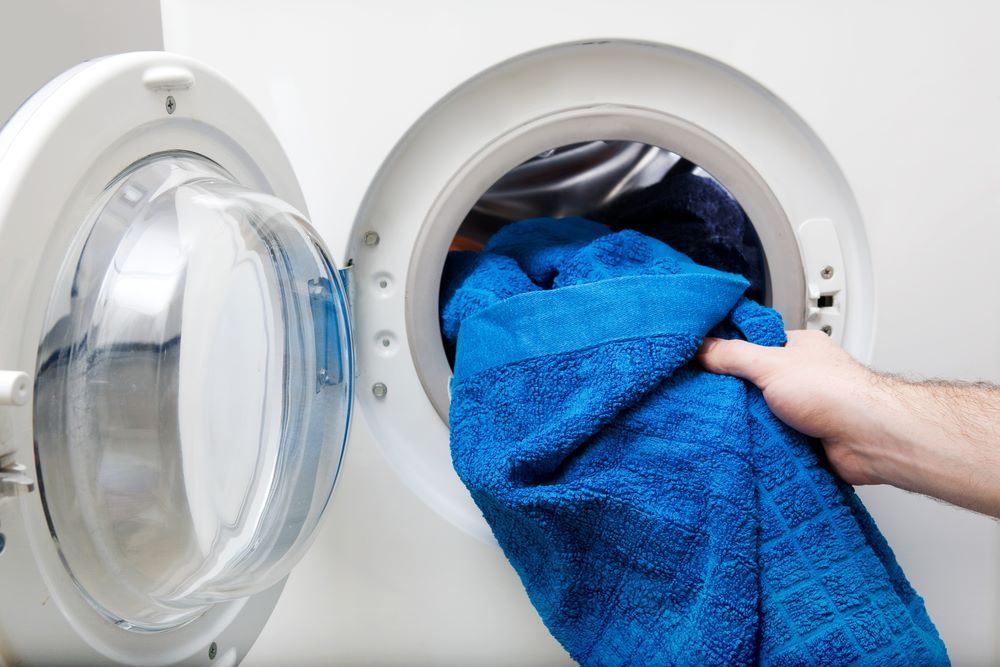 A is Taking a Towel Out of a Washing Machine — Super Suds Laundry in Avoca, QLD