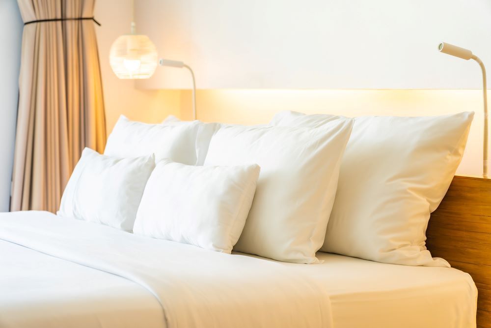 A Bed With White Sheets and Pillows in a Hotel Room — Super Suds Laundry in Avoca, QLD
