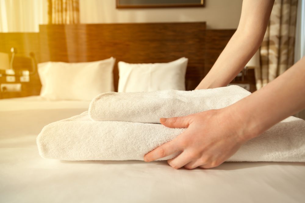 A Woman is Stacking Towels on a Bed — Super Suds Laundry in Avoca, QLD