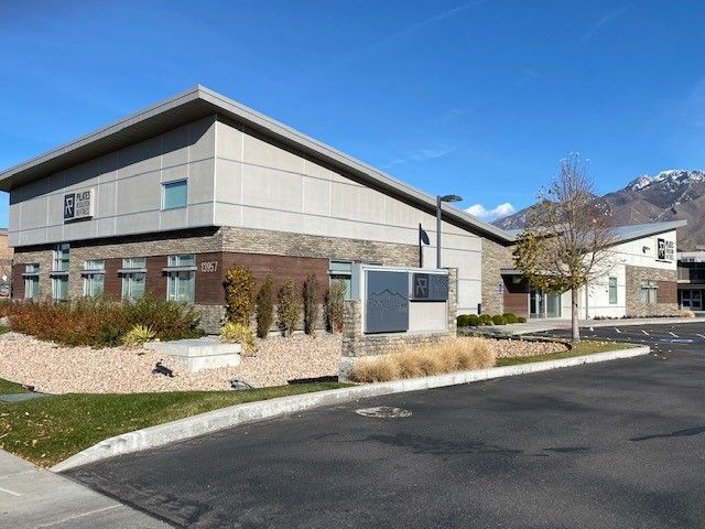 A large building with mountains in the background and a parking lot in front of it