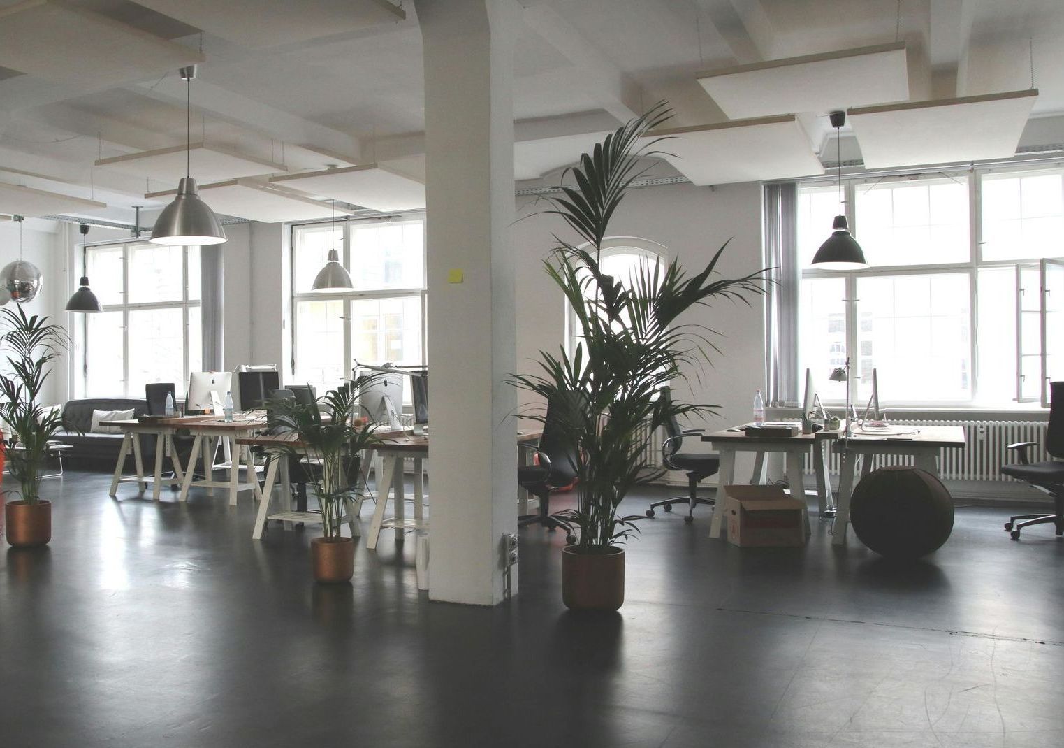 A large office with lots of windows and tables and chairs