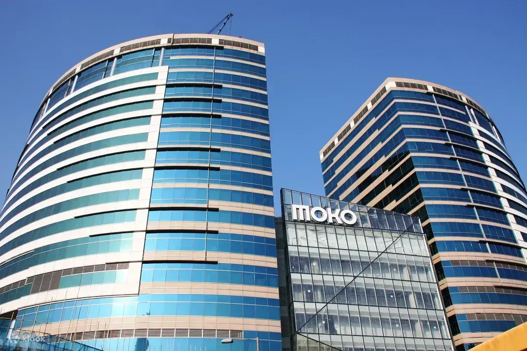 两栋现代化的办公大楼，外墙为蓝色玻璃，中间可见“MOKO”标志。