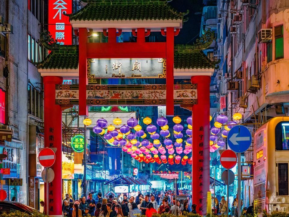 夜晚，唐人街灯火通明，红色华丽的大门；人群、灯笼和商店。