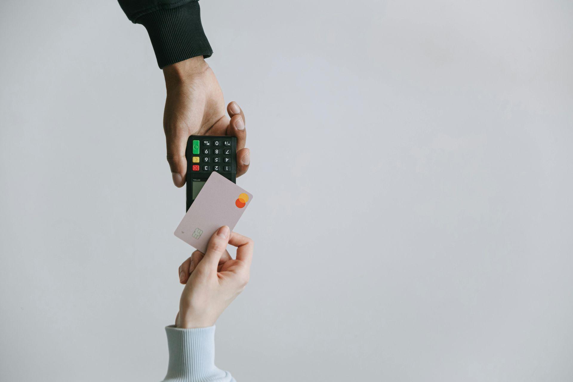 Person using a credit card to pay for a purchase at a card reader.