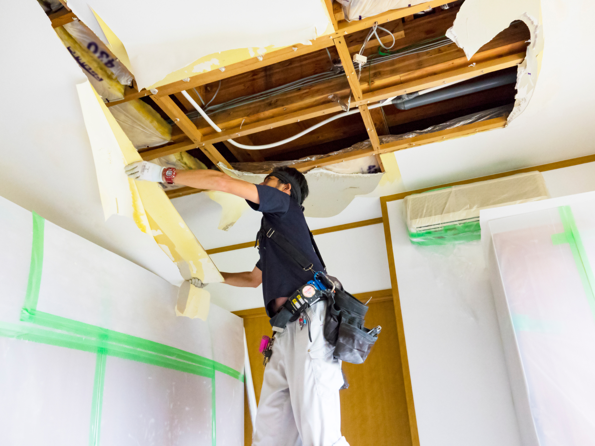 A man is working on the ceiling of a room.