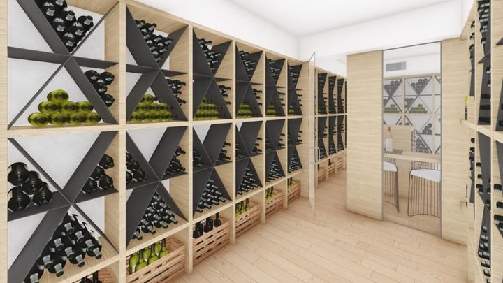 Luminosa cantina con scaffalature in legno, bottiglie nere e un piccolo tavolo per le degustazioni.