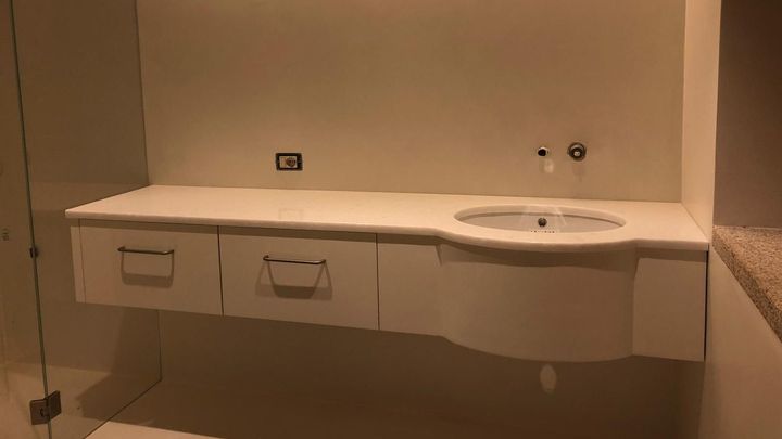 Mobile da bagno bianco con lavabo e cassetti, su una parete beige.