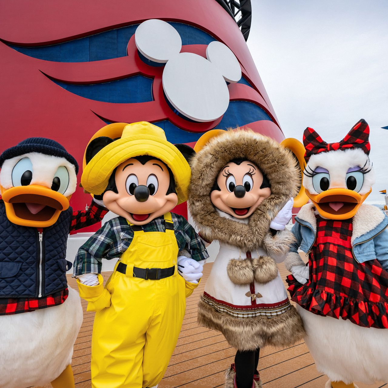 Mickey and Minnie with Donald and Daisy in colorful Disney costumes posing in front of a Mickey backdrop