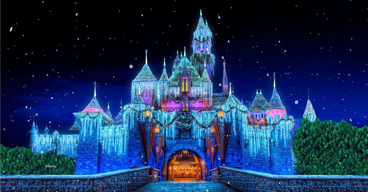 A brightly lit fairy-tale castle glowing blue and pink against a starry night sky