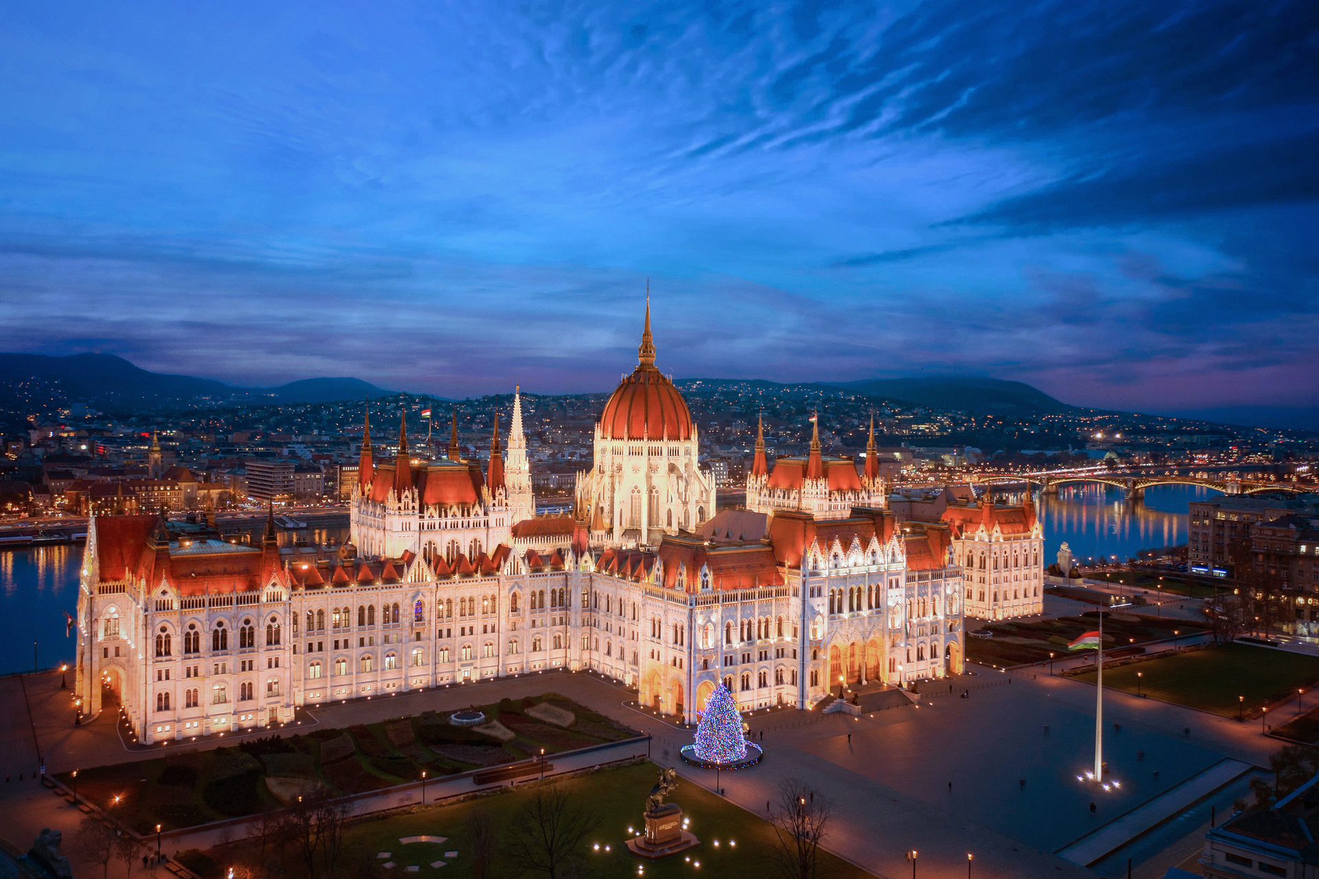 The illuminated Hungarian Parliament Building in Budapest at twilight, reflecting on the Danube River.