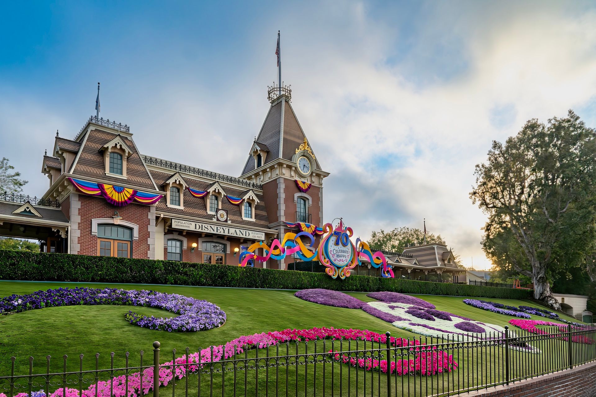 The entrance to Disneyland Park in Anaheim, California, featuring the Main Street train station and a floral Mickey Mouse.