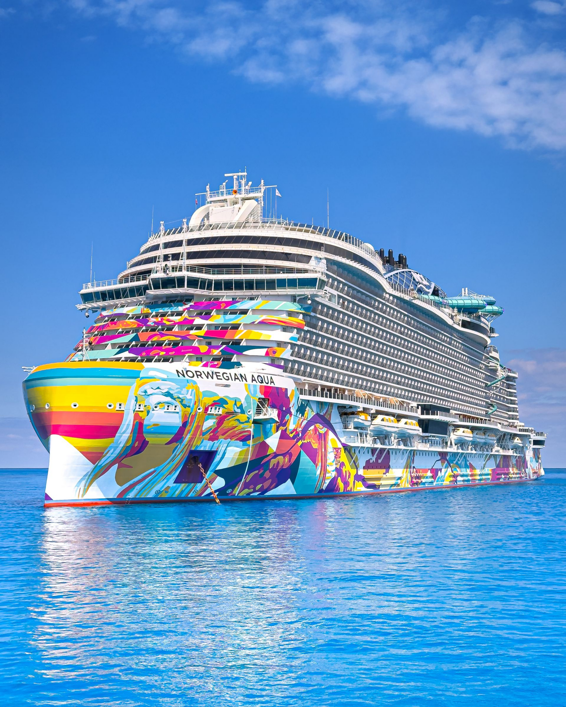 Colorful cruise ship with rainbow mural sailing on calm blue water under a clear sky