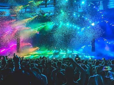 Crowd at a concert under colorful blue, green, and pink stage lights and confetti