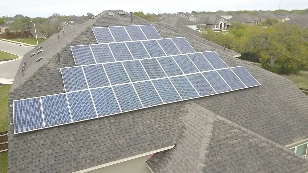 Rooftop solar panels installed on a gray shingled house in a suburban neighborhood.