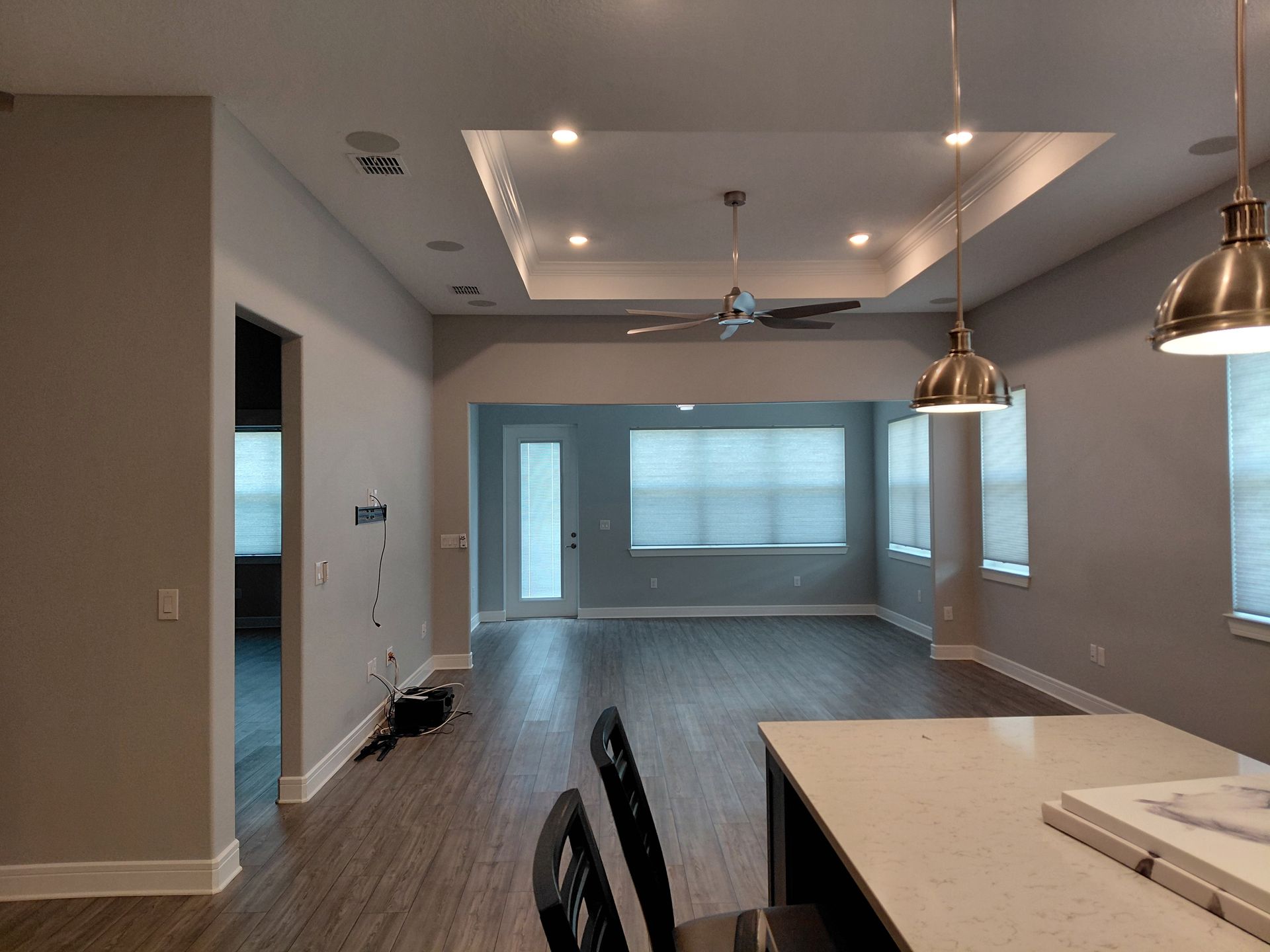 Modern open-plan kitchen and living area with pendant lights, gray walls, and large windows
