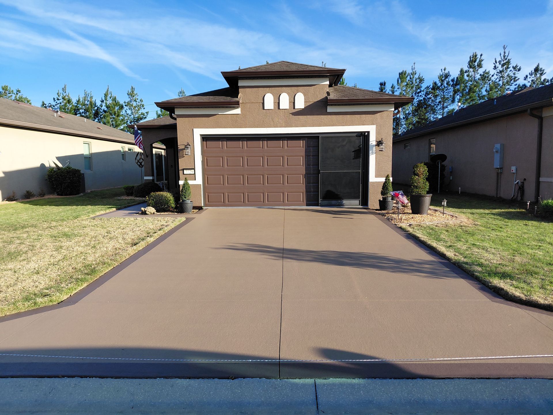 Suburban house with a two-car garage and wide concrete driveway under a clear sky
