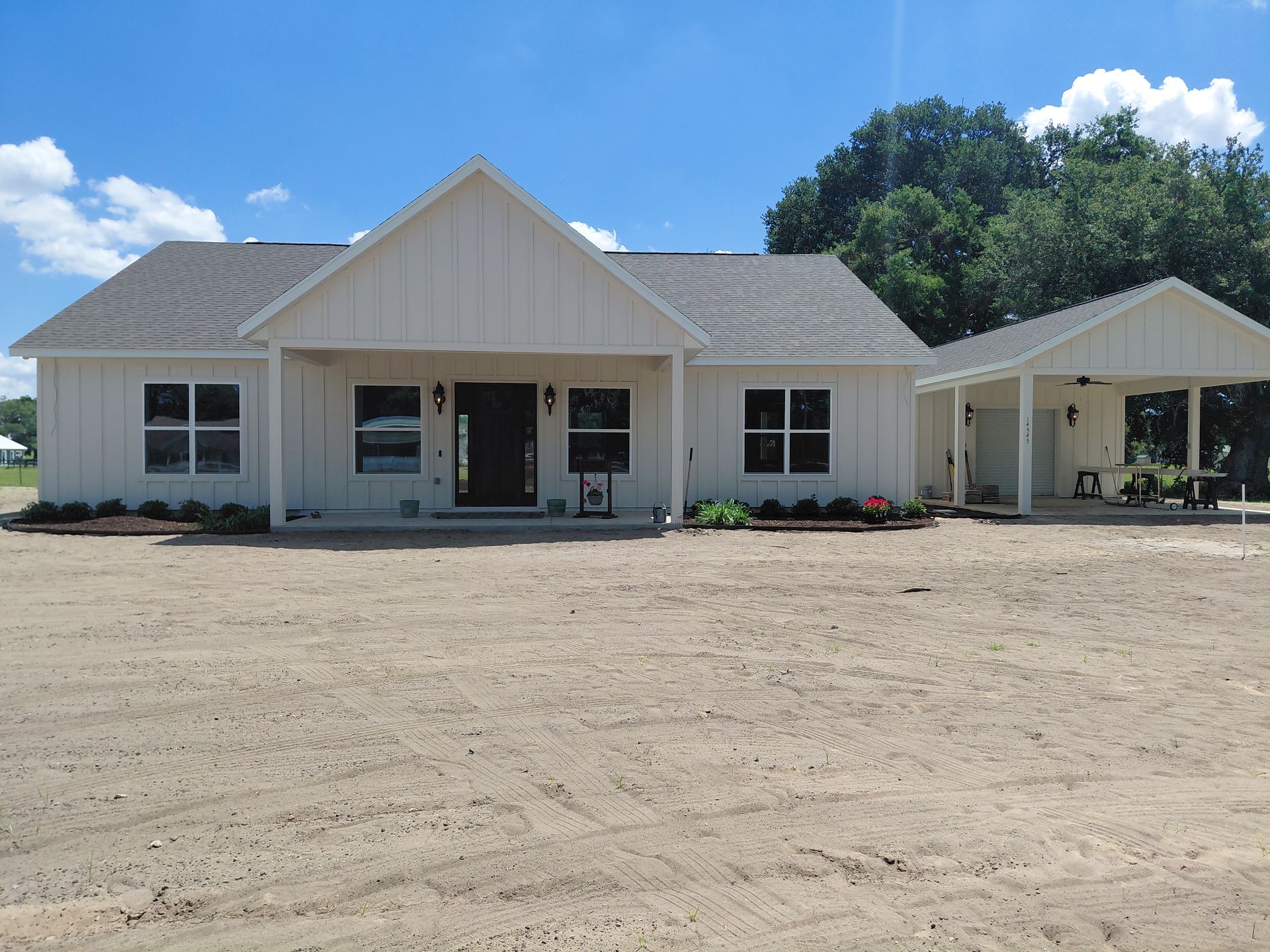 White single-story house with a front porch and gravel yard under a blue sky