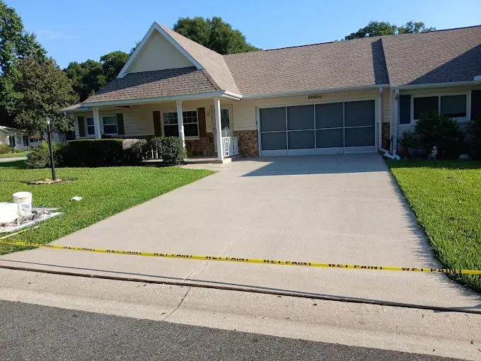 House with driveway, lawn, and caution tape. Yellow siding, brown roof, green grass.