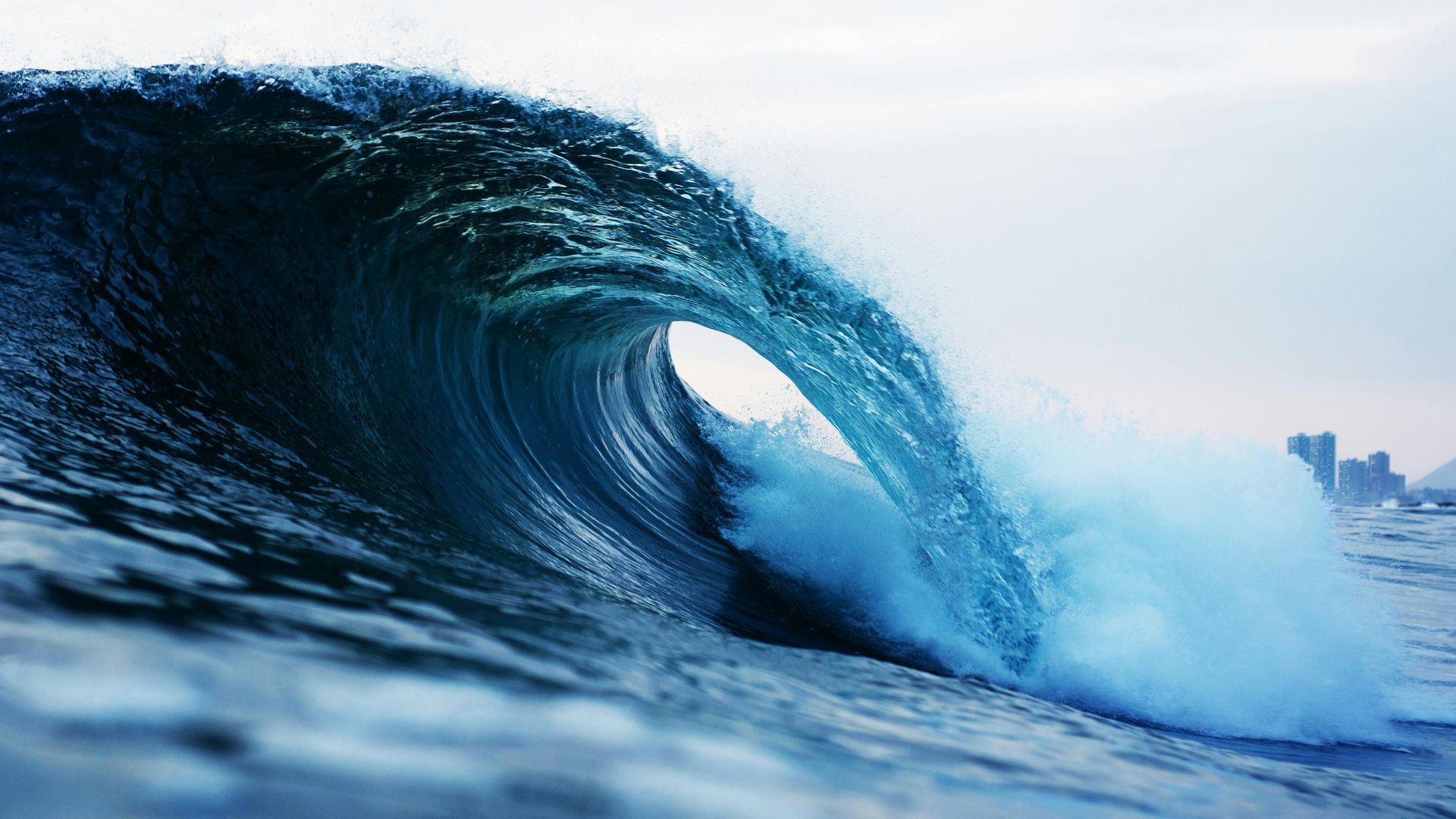 A large wave in the ocean is breaking on the shore.