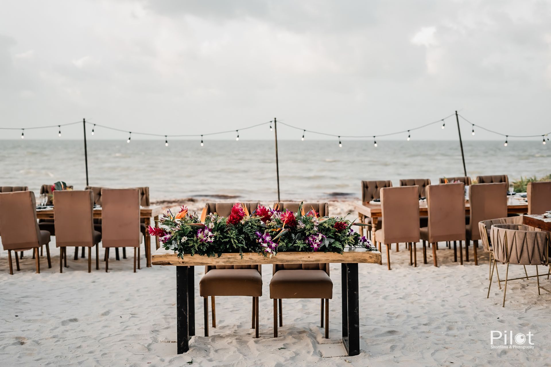Una mesa con flores está en la playa.