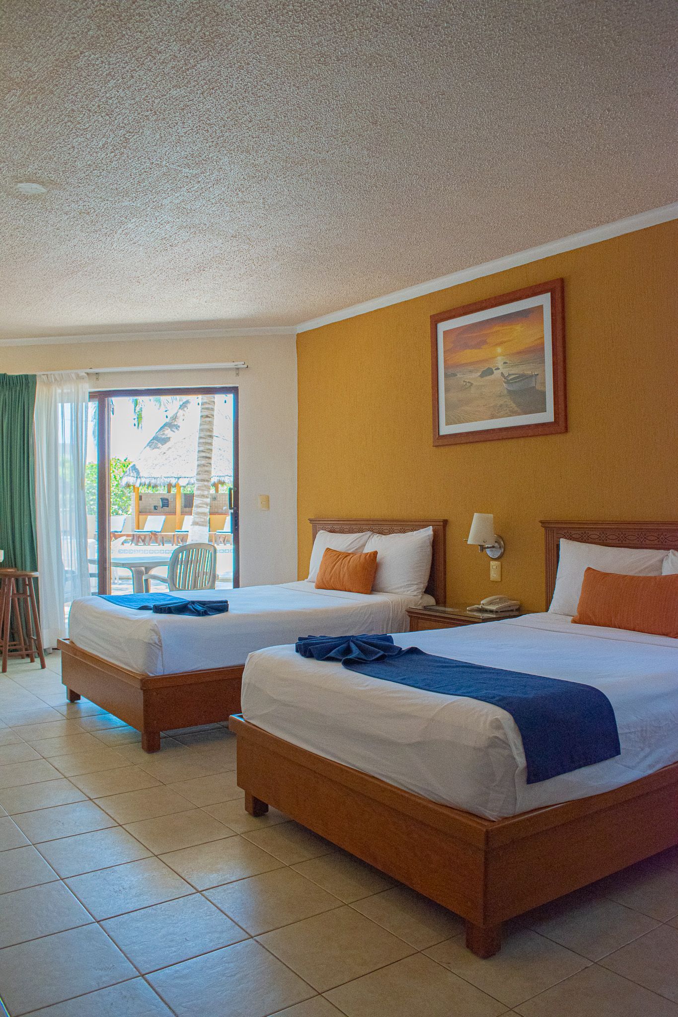 Una habitación de hotel con dos camas y una puerta corrediza de cristal.