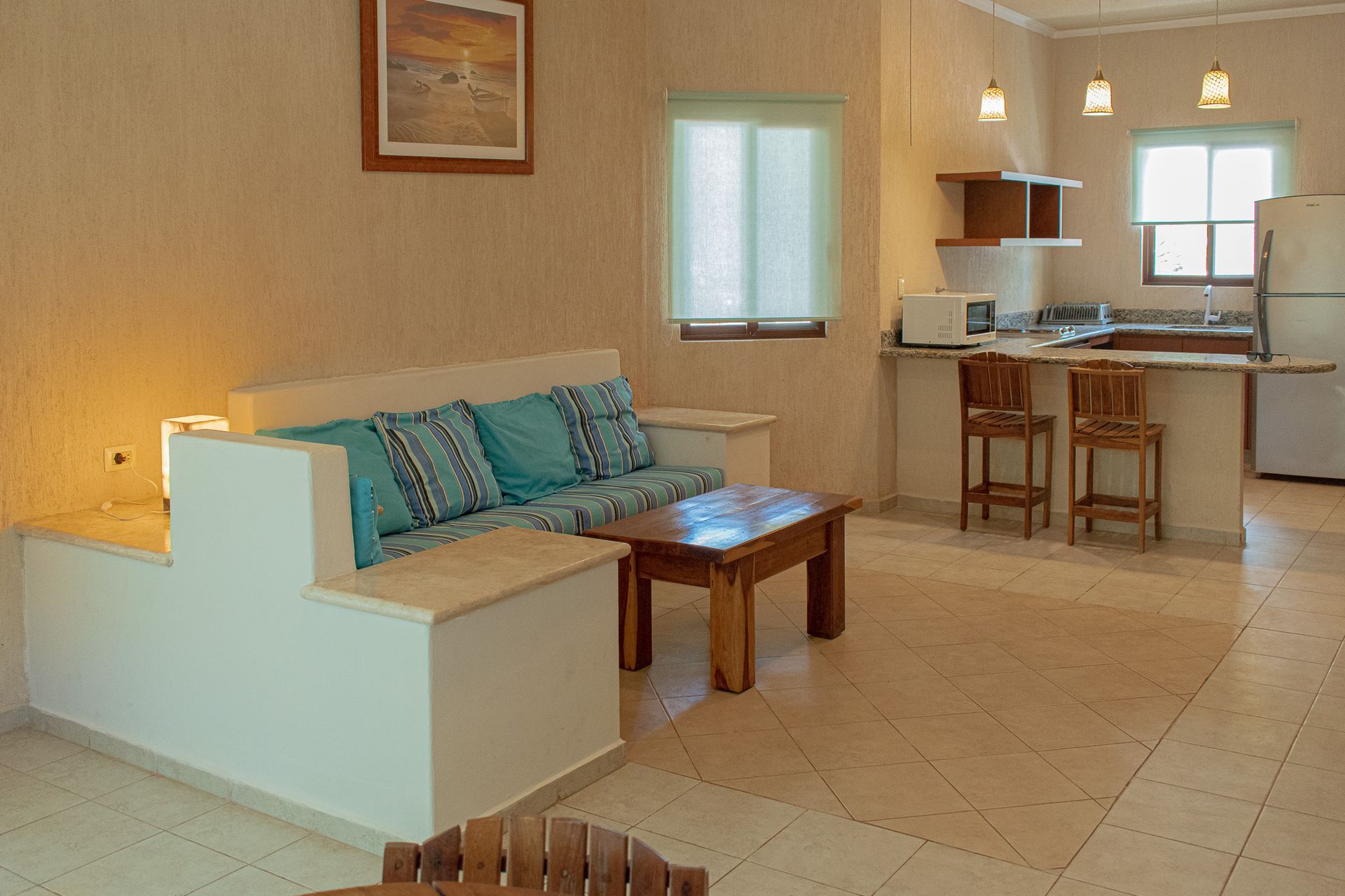 Una sala de estar con sofá, mesa, sillas y una cocina en Tecnohotel Beach.