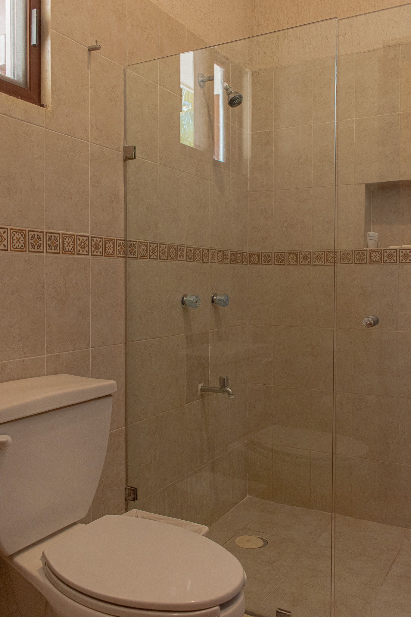 Un baño con inodoro, ducha y ventana Tecnohotel Beach.