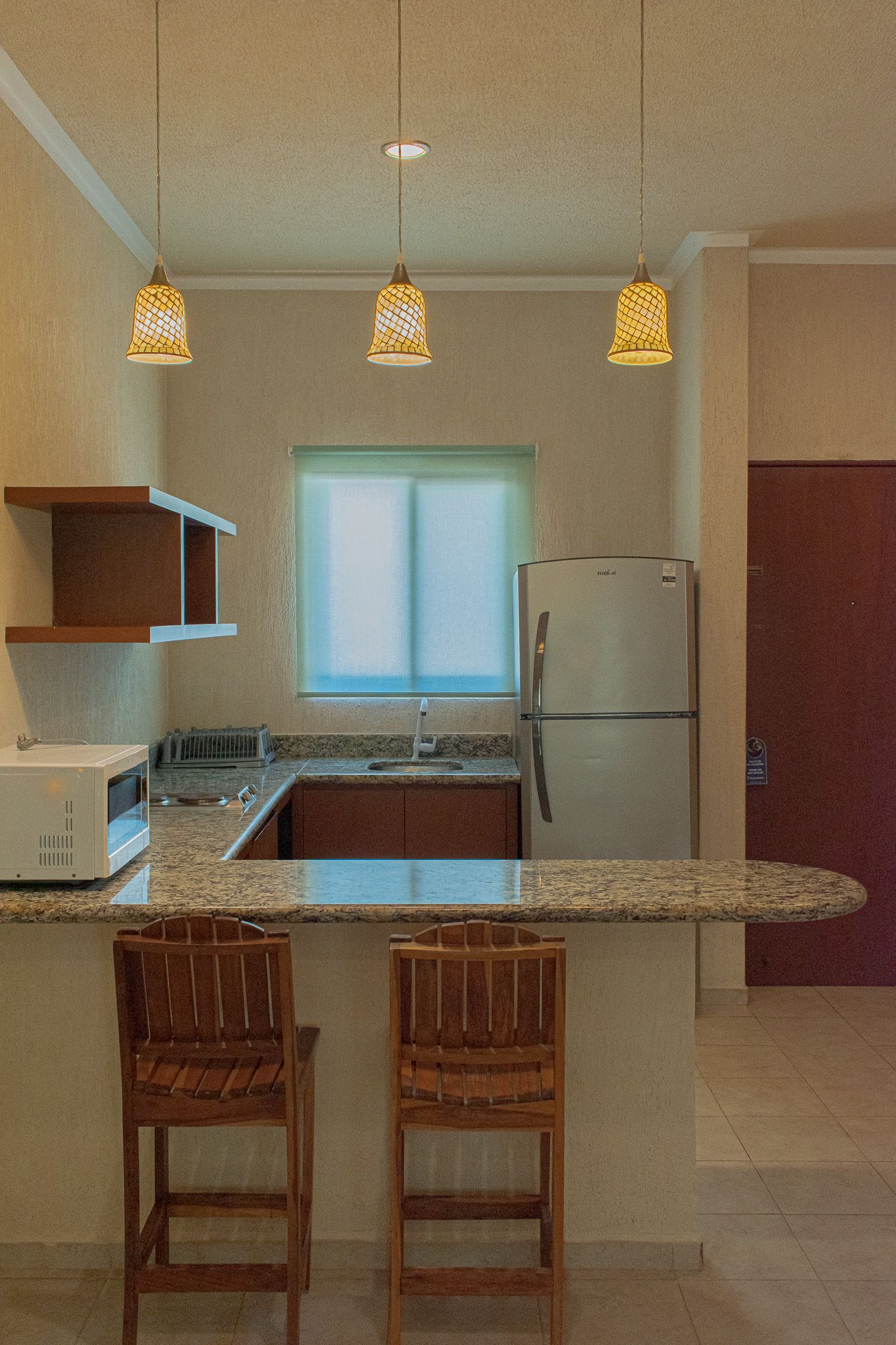 Una cocina con frigorífico, microondas, fregadero y taburetes en Tecnohotel Beach.