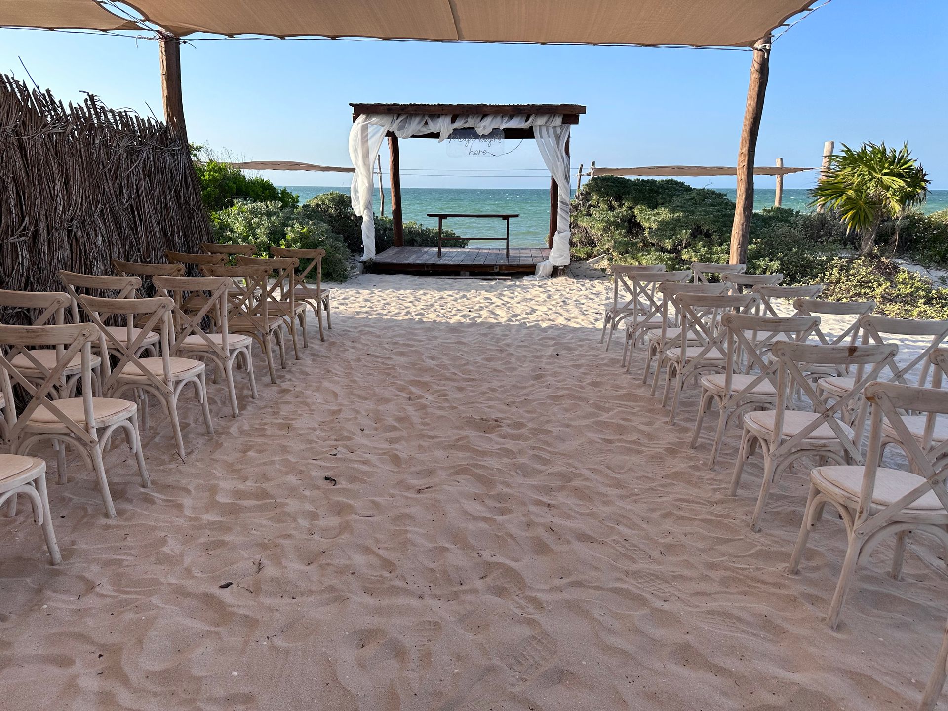 Una fila de sillas están alineadas en una playa de arena frente a un mirador.