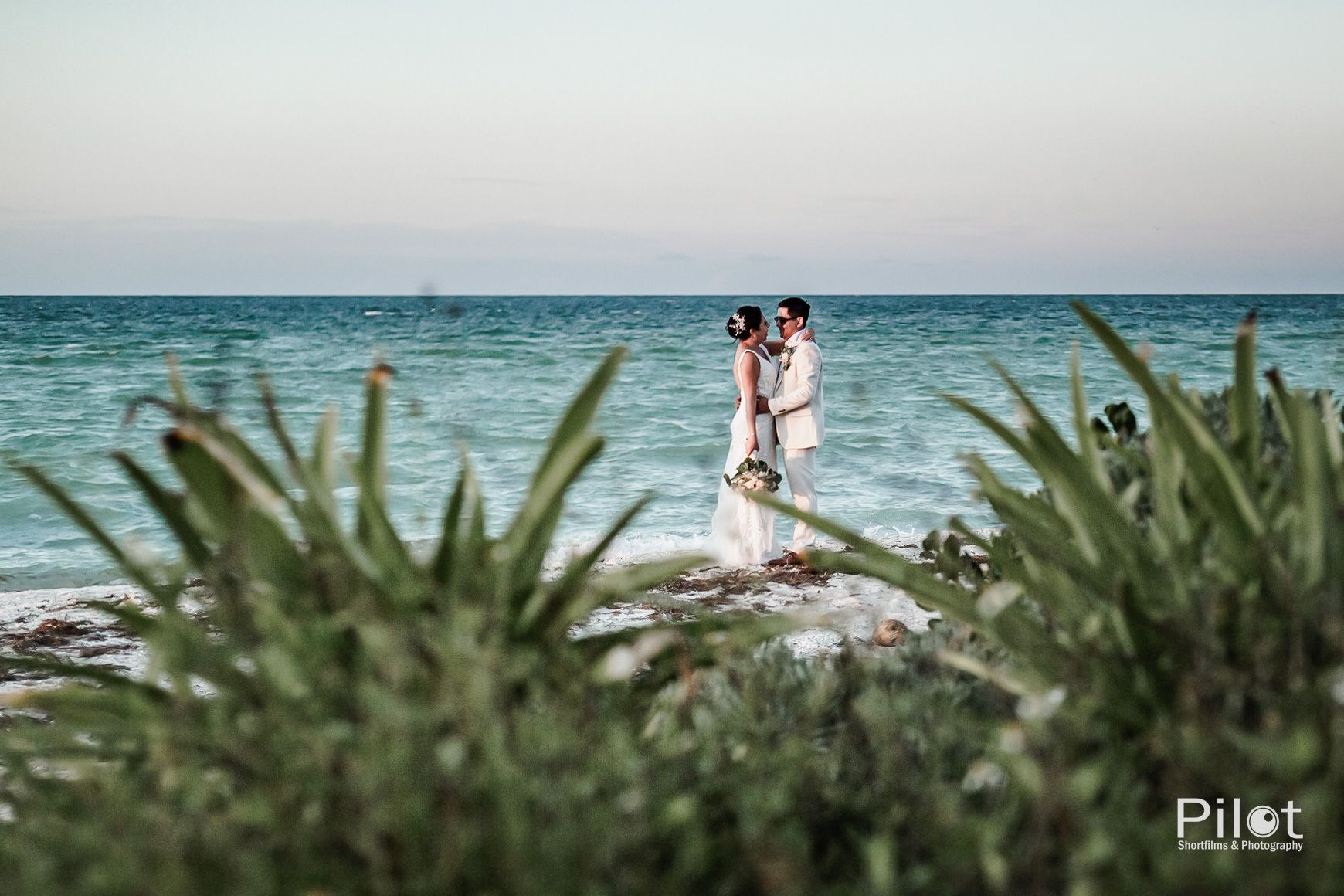 Una novia y un novio posan para una foto en la playa.