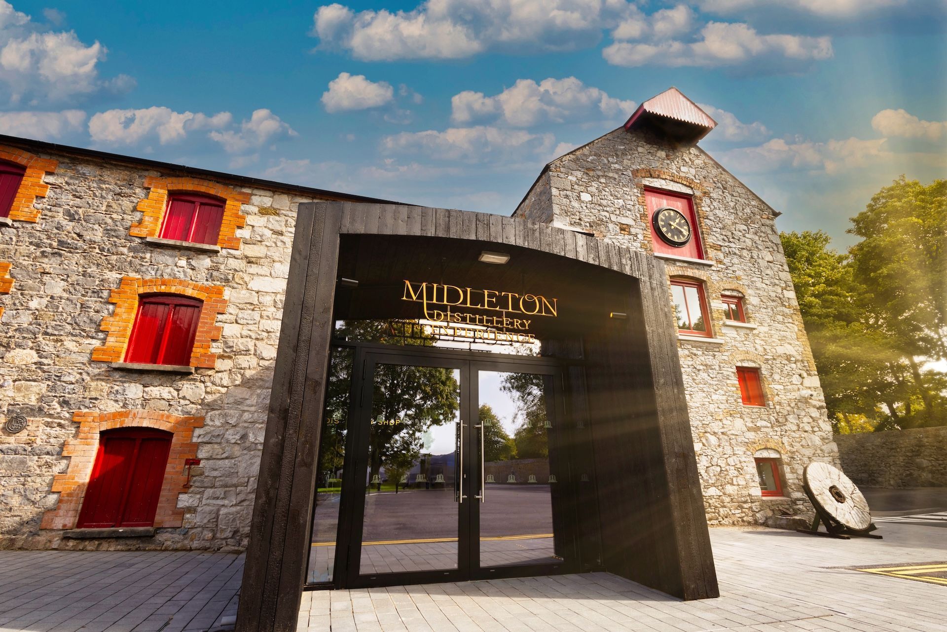 Stone building with red window frames and an arched entrance under a sign reading 