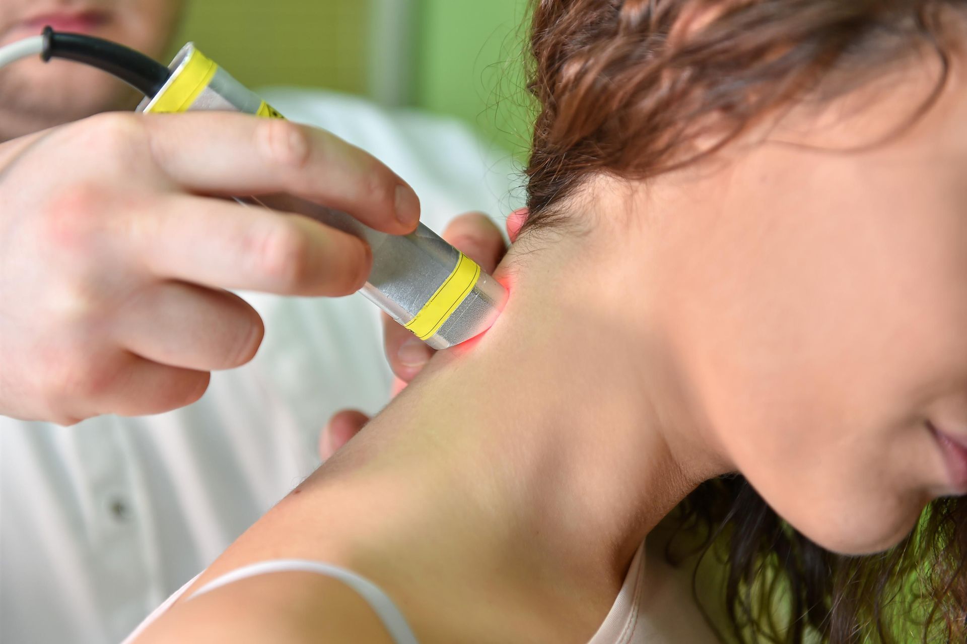 Therapist using a handheld device on a woman’s neck during a treatment session
