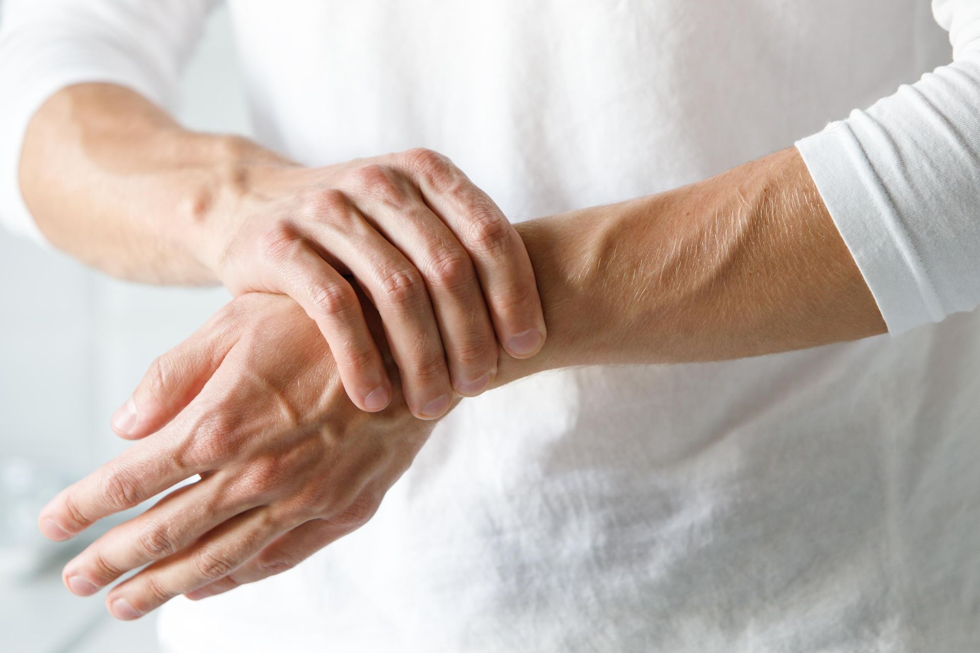 Person holding a painful wrist with one hand, suggesting a wrist strain or injury