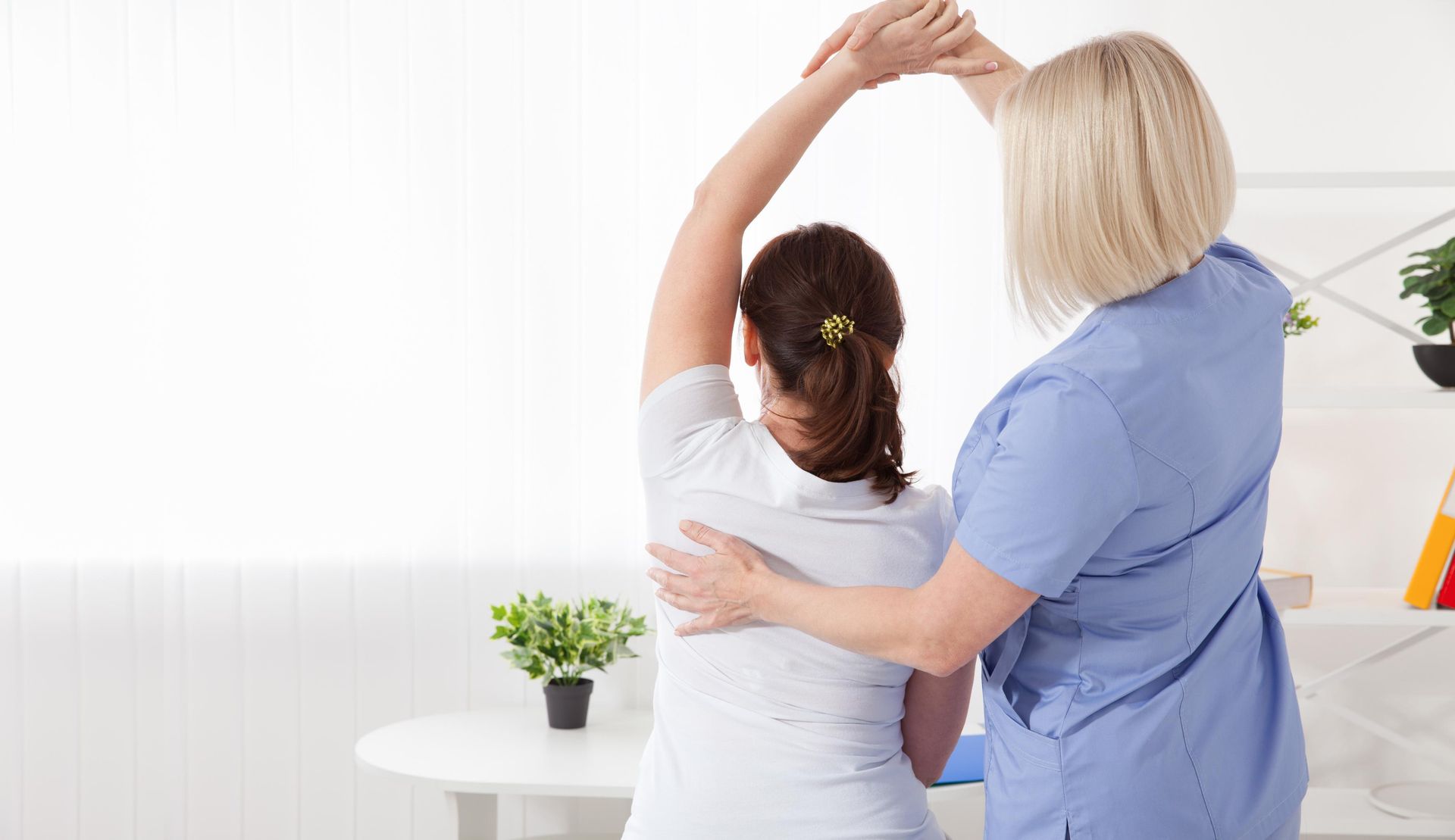 Two healthcare workers stretching together in a bright clinic room
