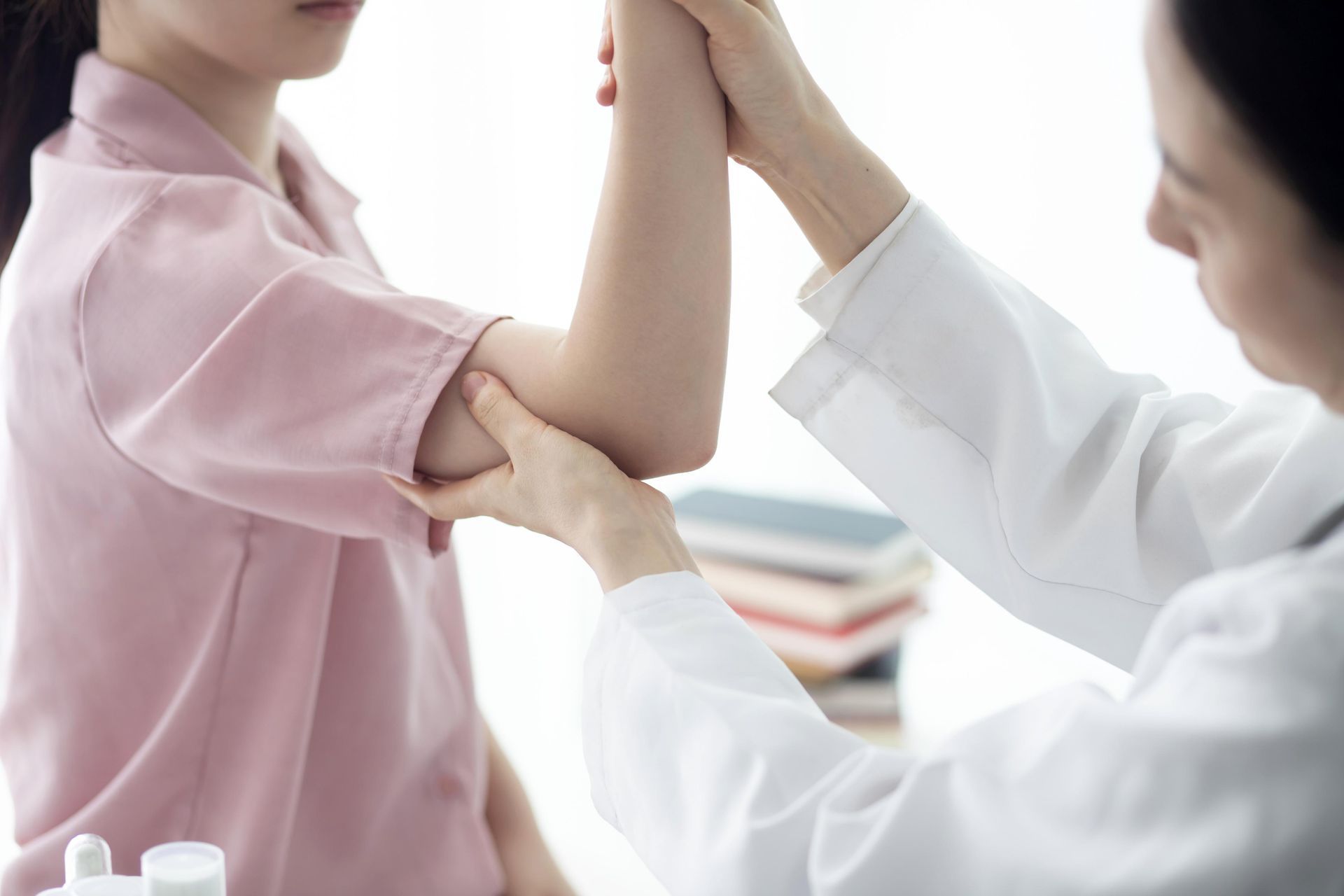 Doctor examining a patient’s arm in a bright clinic, with a hand supporting the elbow