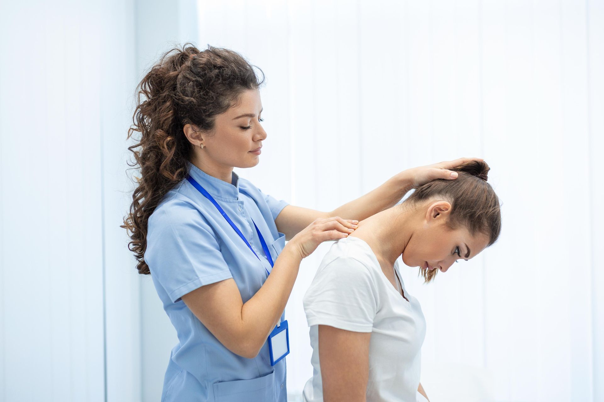 Therapist giving neck massage to a patient in a bright clinic room