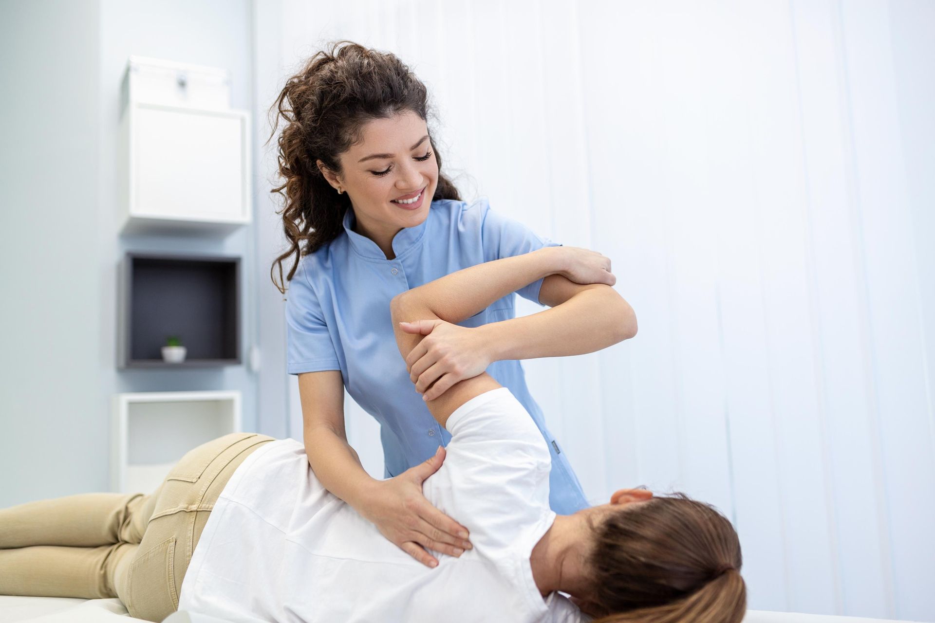 Physical therapist helping a patient stretch their arm on a treatment table