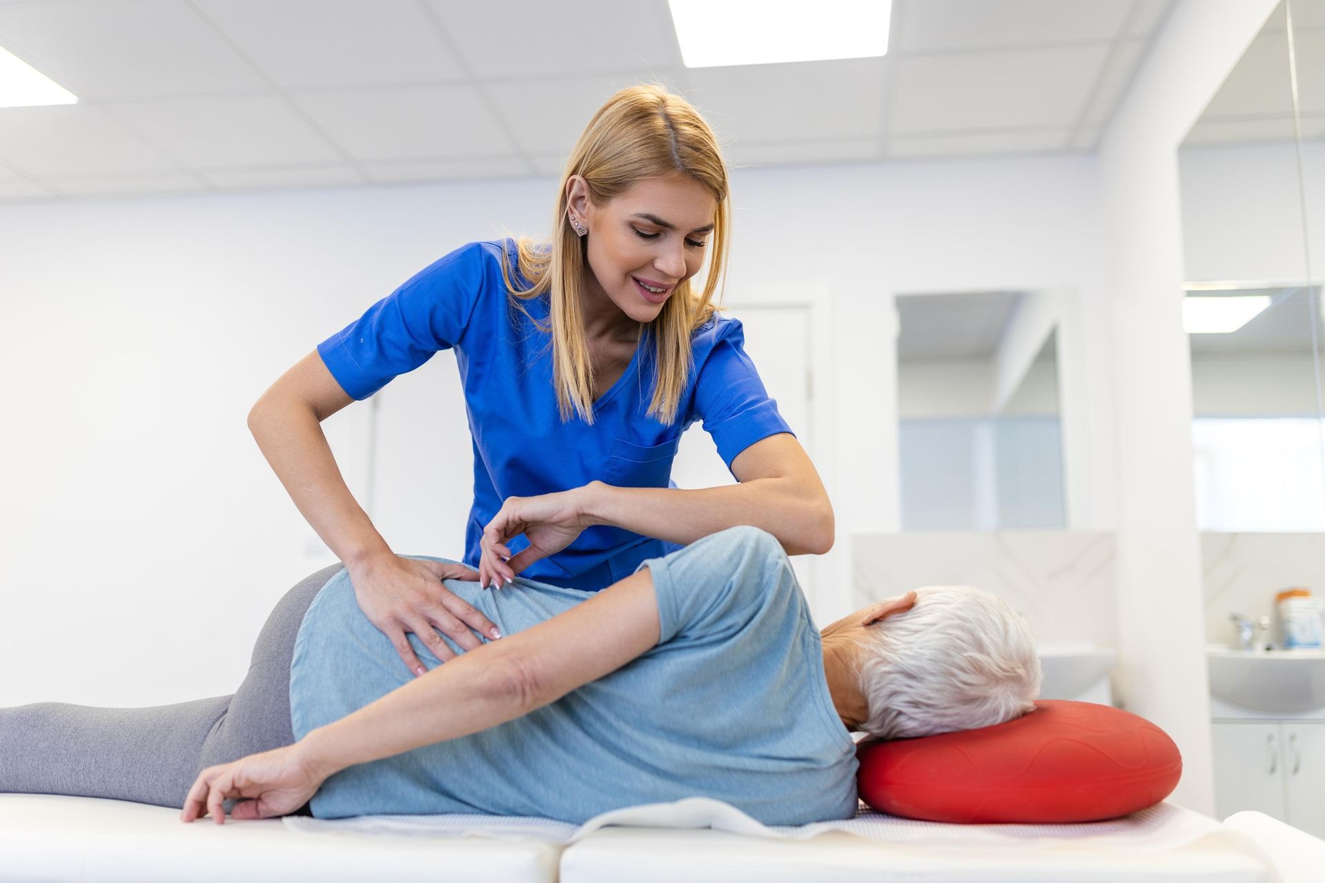 Massage therapist working on a client’s back in a bright treatment room